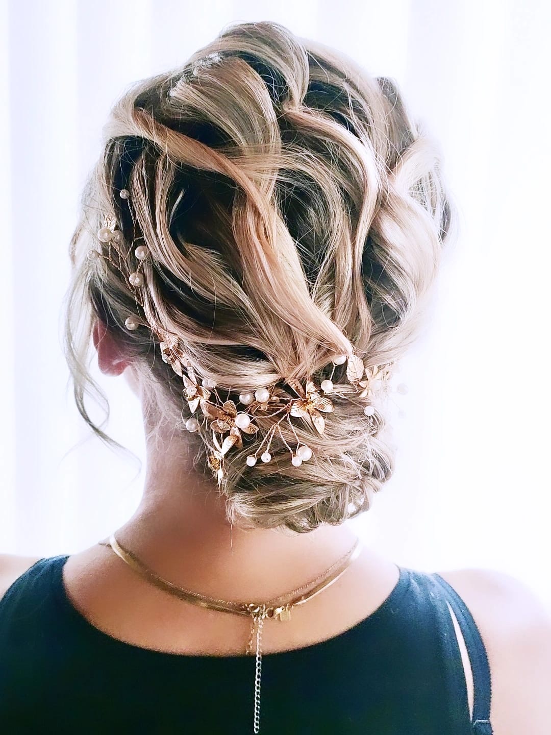 Chignon bohème torsadé avec vigne de fleurs dorées, invitée d'honneur en robe bleu nuit