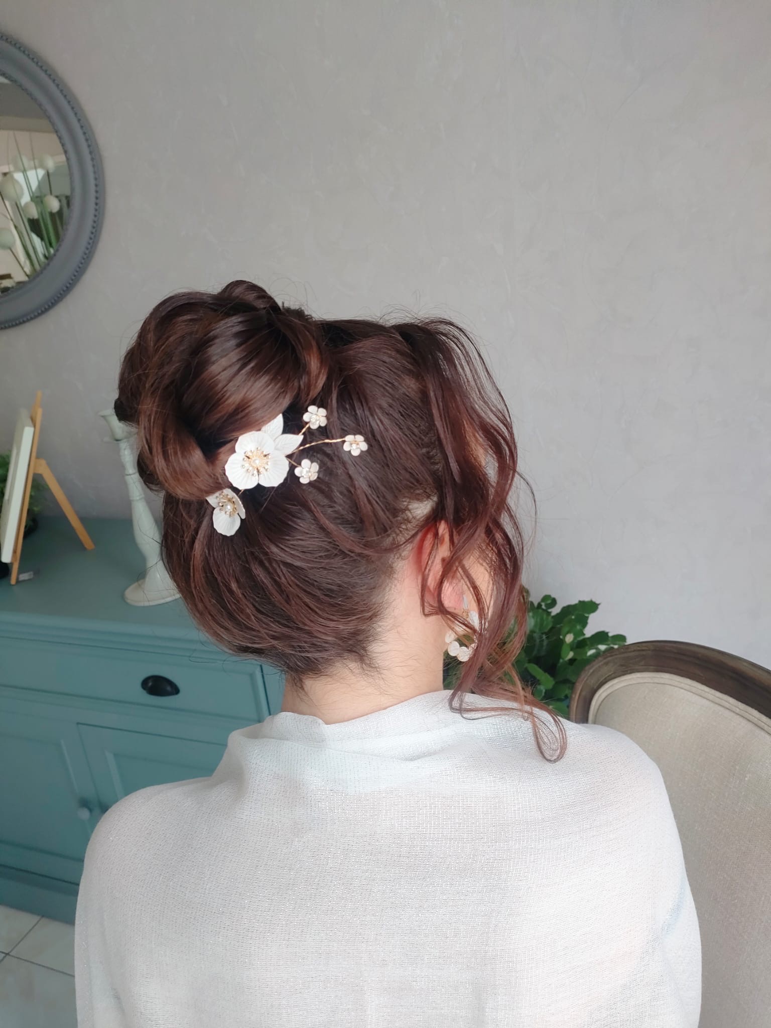Chignon haut avec pic à fleurs blanches réalisé lors d'un essai coiffure à domicile