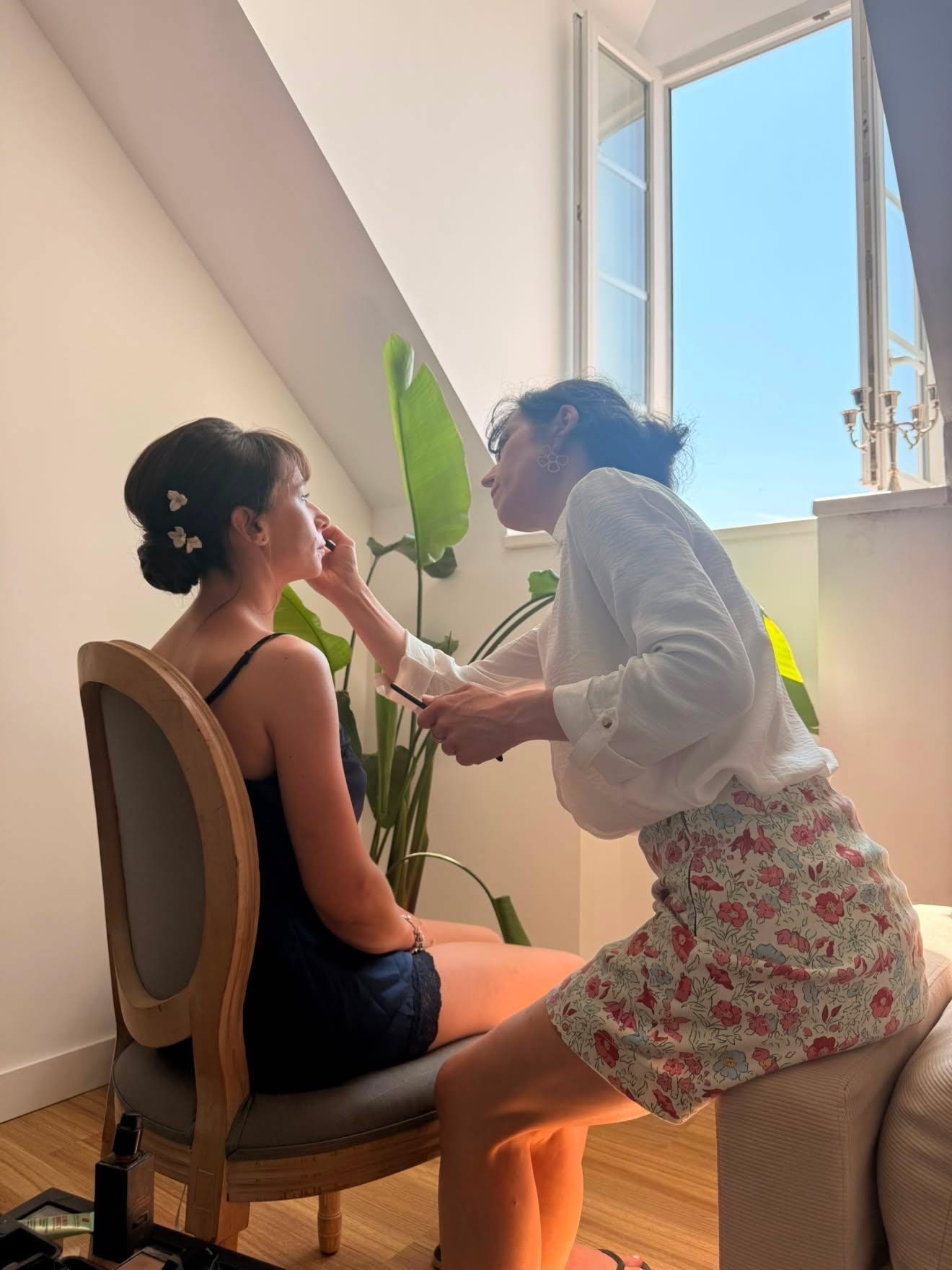 Maquillage d'une cliente à domicile dans la lumière de la fenêtre, le matin du jour J