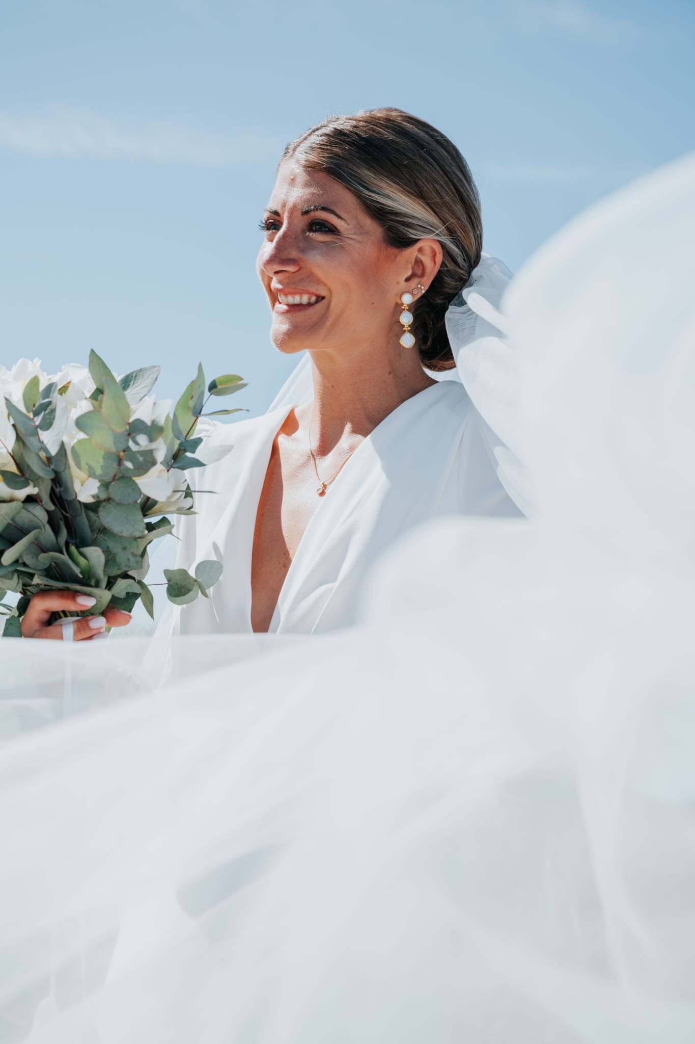 Mariée au voile flottant sous le ciel bleu de la Côte de Granit Rose